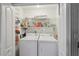 Bright laundry room with washer, dryer, and storage shelves at 2243 Worthington Greens Dr, Sun City Center, FL 33573