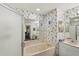 Well-lit main bathroom with tub, shower, dual sinks, and floral wallpaper at 2243 Worthington Greens Dr, Sun City Center, FL 33573