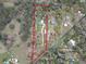 Aerial view highlighting the expansive property, featuring wooded areas, structures, and road frontage at 25590 Olympia Rd, Brooksville, FL 34601