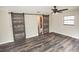 Bedroom features wood-look floors, barn-style doors to the bathroom, and modern ceiling fan at 25590 Olympia Rd, Brooksville, FL 34601