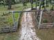 Aerial view of a gated entrance to a secluded property with a rustic fence and natural surroundings at 25590 Olympia Rd, Brooksville, FL 34601