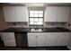 Updated kitchen features white cabinets, dark countertops, stainless dishwasher and undermount sink at 25590 Olympia Rd, Brooksville, FL 34601