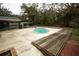 Backyard pool featuring a unique shape, surrounded by a concrete deck and wooden platform for relaxation and entertainment at 25590 Olympia Rd, Brooksville, FL 34601