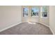 Sunlit bedroom with neutral carpet and three windows offering pleasant neighborhood views at 30280 Southernwood Ct, Wesley Chapel, FL 33543