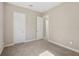 Empty bedroom featuring light beige walls, neutral carpet, and two white doors at 30280 Southernwood Ct, Wesley Chapel, FL 33543