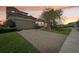 Paver driveway leading to a two car garage with manicured lawn at 30280 Southernwood Ct, Wesley Chapel, FL 33543