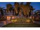 Beautiful two-story home with well-manicured landscaping, including palm trees and illuminated shrubbery, and a two-car garage at 315 Manatee Ln, Tarpon Springs, FL 34689