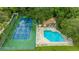 Aerial view of tennis court and community pool with lounge chairs, surrounded by lush greenery at 318 Parkside Ln, Safety Harbor, FL 34695