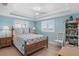 Bright bedroom features a ceiling fan, tray ceiling, and two windows with plantation shutters at 330 176Th Avenue Cir, Redington Shores, FL 33708