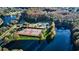 Aerial view of a well-maintained tennis court surrounded by mature trees and community waterways at 3798 Darston St, Palm Harbor, FL 34685