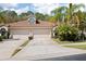 Charming home featuring a tile roof, two-car garage, and beautiful tropical landscaping with mature palm trees at 3798 Darston St, Palm Harbor, FL 34685