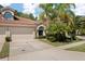 Charming home featuring a tile roof, two-car garage, and beautiful tropical landscaping with mature palm trees at 3798 Darston St, Palm Harbor, FL 34685