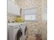 Bright laundry room featuring a washer and dryer, floral wallpaper and overhead cabinet storage at 3798 Darston St, Palm Harbor, FL 34685