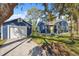 Charming blue house with a detached garage, yellow door, and mature tree coverage at 502 W Hanna Ave, Tampa, FL 33604