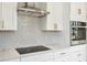 Modern kitchen with white cabinets, stainless steel appliances, quartz countertops and stylish backsplash at 502 W Hanna Ave, Tampa, FL 33604