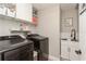Modern laundry room features black washer and dryer, white cabinets and white tile backsplash at 5441 Worthington Loop, Palm Harbor, FL 34685