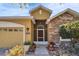 Inviting home exterior featuring a screened entrance, stone accents, potted plants, and a two-car garage at 6432 Twin Bridges Dr, Zephyrhills, FL 33541