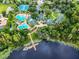 This aerial view features a resort-style pool, tennis courts, clubhouse and lake with a dock at 7309 Night Heron Dr, Land O Lakes, FL 34637