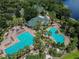 Aerial view of a community pool area featuring lounge chairs, lush landscaping, and palm trees at 7309 Night Heron Dr, Land O Lakes, FL 34637