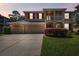 Charming two-story home features a spacious three-car garage, red shutters and a well-manicured lawn at 7309 Night Heron Dr, Land O Lakes, FL 34637