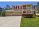 Charming two-story home features a spacious three-car garage, red shutters and a well-manicured lawn at 7309 Night Heron Dr, Land O Lakes, FL 34637