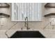 Close up view of a stylish black kitchen sink with a modern faucet and marble countertops at 7309 Night Heron Dr, Land O Lakes, FL 34637