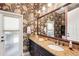 Bathroom with granite countertop, decorative wallpaper, and large mirror at 8057 Rio Bella Pl, Bradenton, FL 34201