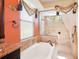 Luxurious bathroom featuring a soaking tub, glass shower, and decorative window treatments for added privacy at 8057 Rio Bella Pl, Bradenton, FL 34201