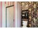 Bathroom features a unique wallpaper, tiled shower, and shelving unit over the toilet at 8057 Rio Bella Pl, Bradenton, FL 34201