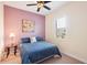 Cozy bedroom with a full-sized bed, lamp on glass side table, shuttered window, and purple accent wall at 8057 Rio Bella Pl, Bradenton, FL 34201