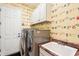 Laundry room with clothes-themed wallpaper, wash sink, and white cabinets at 8057 Rio Bella Pl, Bradenton, FL 34201