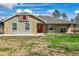 Charming single-story home featuring a brick facade, covered porch, and a vibrant red front door at 9580 Grove Rd, Brooksville, FL 34613