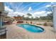 Inviting backyard pool with stone retaining wall, shade sails, and brick paver patio under sunny, partly cloudy skies at 9580 Grove Rd, Brooksville, FL 34613