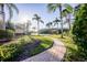 Lush backyard with a brick walkway, mature palm trees, and a view of the lake at 10411 Cory Lake Dr, Tampa, FL 33647