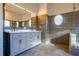 Modern bathroom featuring a double vanity, unique round window, and glass-enclosed shower for a luxurious experience at 10411 Cory Lake Dr, Tampa, FL 33647