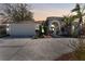 Charming single-story home featuring lush landscaping, a two-car garage, and a welcoming front entrance at dusk at 10408 Double Bayou Way, Tampa, FL 33615