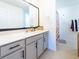 Bathroom vanity with framed mirror and white countertop, complemented by gray cabinetry and neutral tiling at 1107 Brenton Leaf Dr, Ruskin, FL 33570