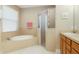 Bright bathroom features a soaking tub, glass shower, and vanity with wood cabinets at 11749 Summer Springs Dr, Riverview, FL 33579