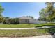 Beige single-story home featuring a well-manicured lawn and a white fence, offering a serene suburban lifestyle at 11749 Summer Springs Dr, Riverview, FL 33579