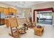 Open-concept living room featuring a modern kitchen, rocking chairs, and a view of the screened-in lanai at 11749 Summer Springs Dr, Riverview, FL 33579