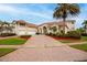Stately home with a brick driveway, meticulously manicured lawn, and a symmetrical facade showcasing timeless elegance at 1314 Jumana Loop, Apollo Beach, FL 33572