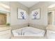 A corner bathtub with marble tile, neutral colors, and floral decorations in the bathroom at 140 Riviera Dunes Way # 404, Palmetto, FL 34221