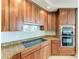 Kitchen featuring granite counters, light wood cabinets, and modern appliances and cooktop at 140 Riviera Dunes Way # 404, Palmetto, FL 34221