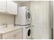Clean laundry room featuring stacked washer and dryer, a sink, and storage cabinets at 140 Riviera Dunes Way # 404, Palmetto, FL 34221