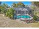Aerial view of a screened-in pool area with a spacious patio surrounded by palm trees and a green lawn at 14048 Bruni Dr, Spring Hill, FL 34609