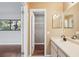 Neutral bathroom featuring a single sink vanity, large mirror, walk-in closet, and view into the bedroom with hardwood floors at 14048 Bruni Dr, Spring Hill, FL 34609