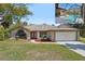Charming single-story home with a manicured front lawn, red mulch accents, and a screened-in pool area at 14048 Bruni Dr, Spring Hill, FL 34609