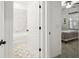 Hallway view of an all white bathroom with white tile, black fixtures and adjacent bedroom at 19632 Fort King Run, Brooksville, FL 34601