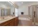 Bathroom displaying a dual sink vanity, large tub and tiled shower with seamless glass at 30142 Sotogrande Loop, Wesley Chapel, FL 33543