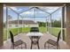 Screened lanai showcasing outdoor seating, table, and serene backyard views at 30142 Sotogrande Loop, Wesley Chapel, FL 33543